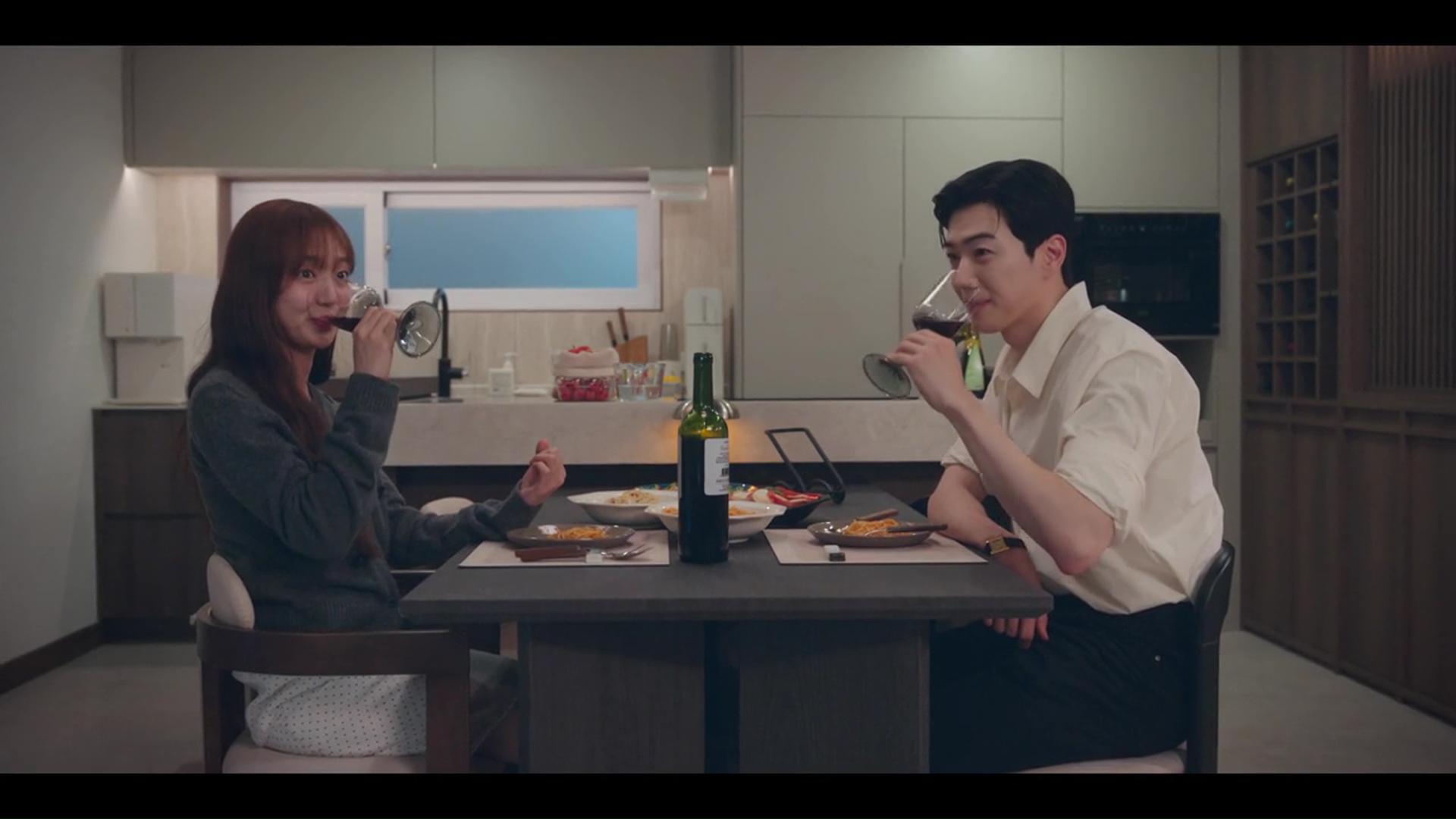 한 남녀가 식탁에 앉아 와인을 마시며 식사하는 모습