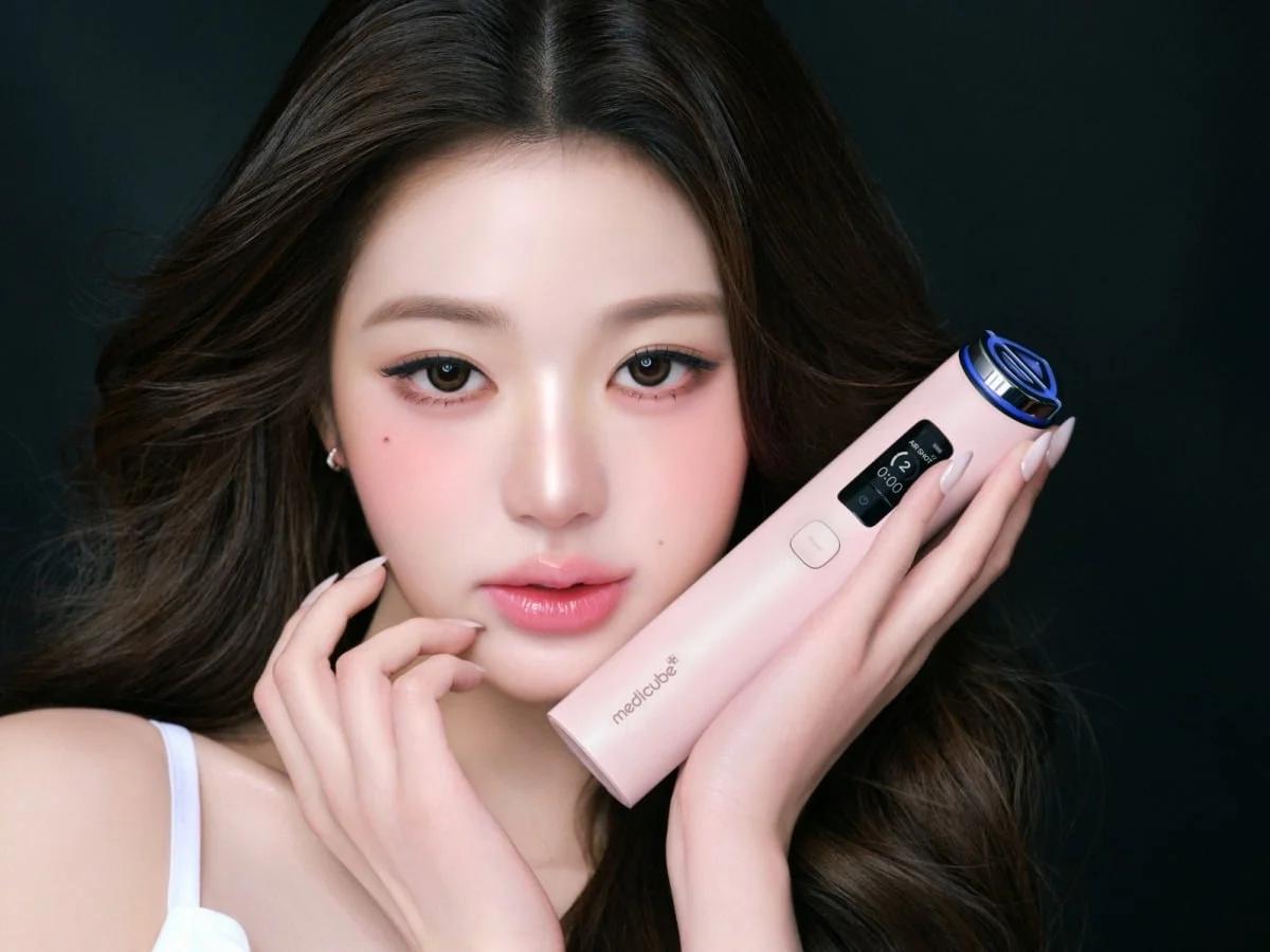 한 여성이 핑크색 뷰티 디바이스를 들고 있다.