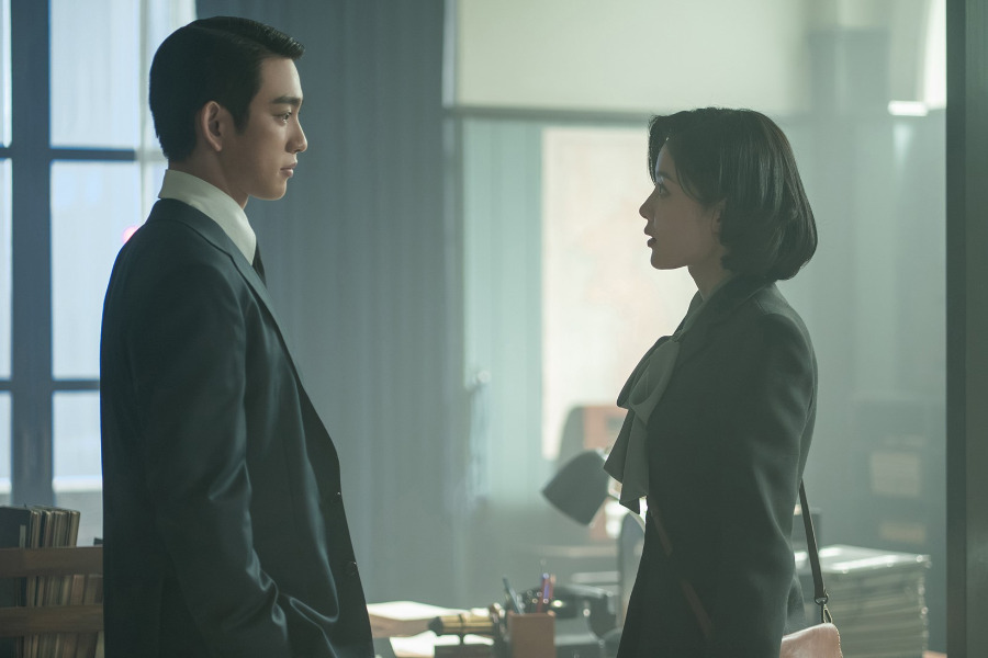 두 배우가 실내에서 마주보고 서 있는 모습.