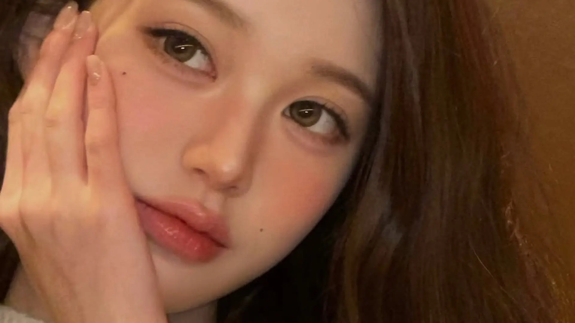 여성이 뺨에 손을 대고 있다.