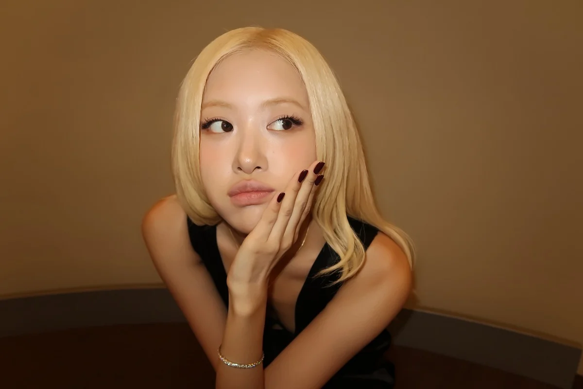 금발의 여성이 손으로 턱을 괴고 카메라를 응시하고 있습니다.