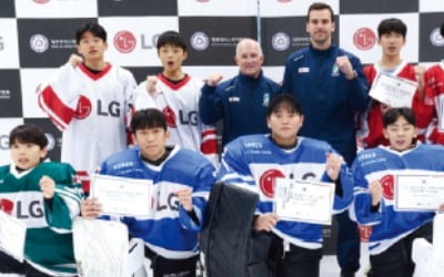 아이스하키 선수들과 코치들이 LG 로고가 있는 유니폼을 입고 단체 사진을 찍고 있다.