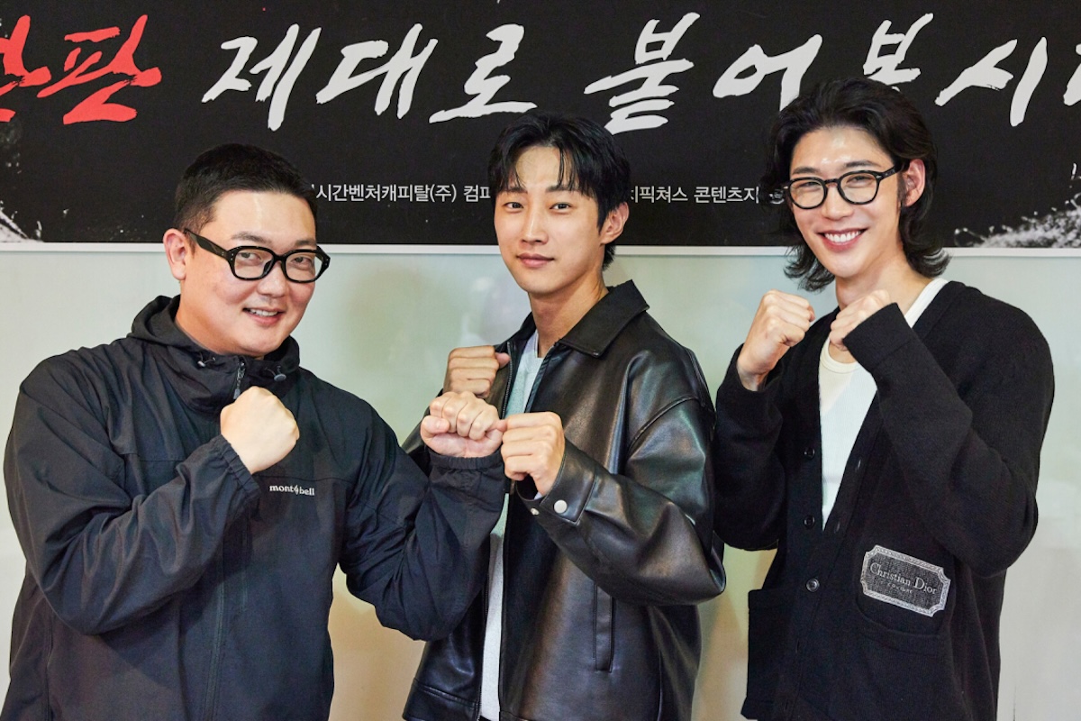세 남자가 주먹을 쥐고 카메라를 보고 있다.