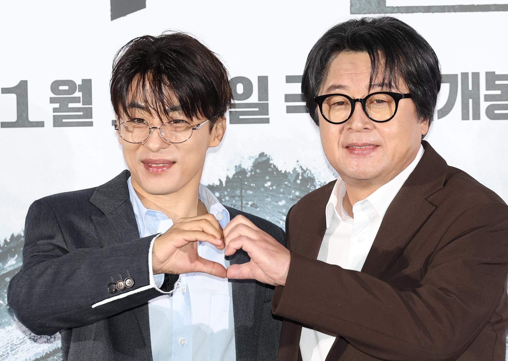 두 남자가 손으로 하트 모양을 만들고 있다.