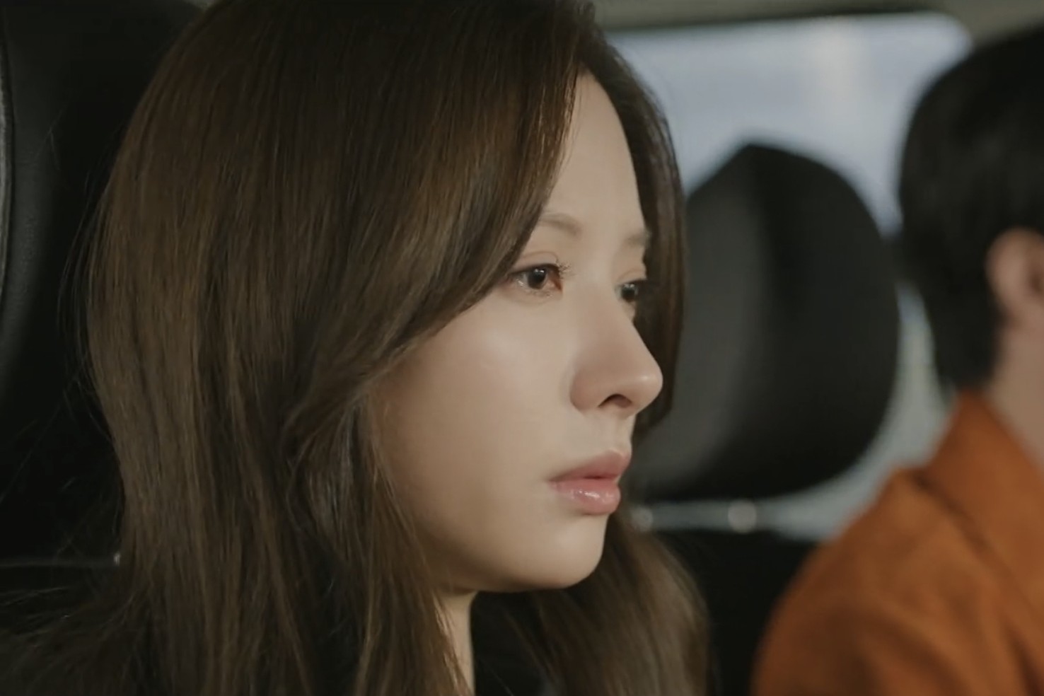 차 안에서 카메라를 응시하는 여성의 모습.